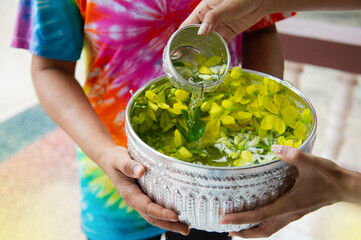 Thai women wearing colorful shirts holding a bowl of flowers and water in a bowl, Thai Songkran Festival.
