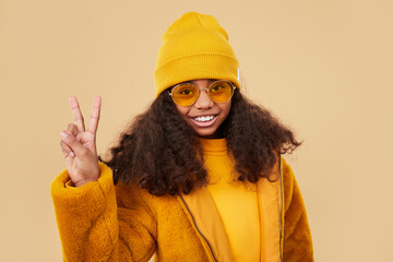 Happy black girl in yellow outfit making V sign