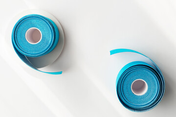 Two blue rolls of kinesiology tape on white background with shadows and podiums, flat lay. Recovery, anti-aging procedures concept. Kinesio taping