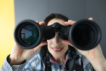 Woman looking through black binoculars and holding it with her hands