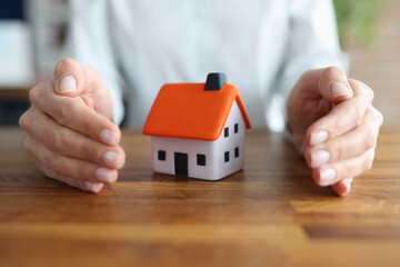 Female hands hugging small toy house closeup