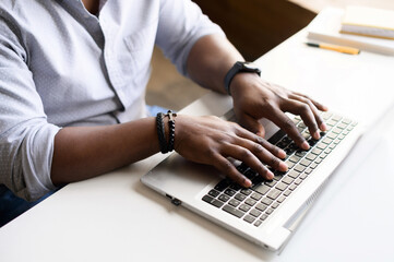 Close up image of male hands with accessories typing text on the laptop keyboard, working,...