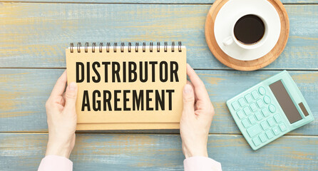 the text of the distribution agreement on a notebook, in the hands against the wooden background of the office table.