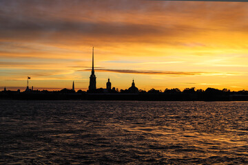 Naklejka premium Sunset over the city on the coast. Beautiful orange sunset over the river, the silhouette of the city at sunrise over the river. Sunset over the Neva River, the silhouette of St. Petersburg.