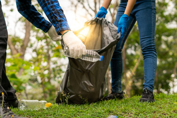 young volunteers collecting garbage in park. Ecology group. Concept of environmental protection....