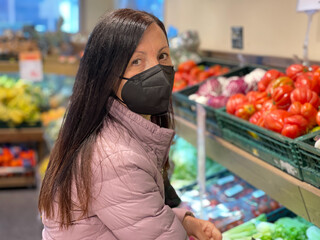 Happy woman wearing black mouth face mask in the food supermarket