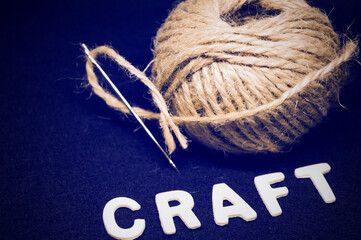 craft a tangle of coarse brown threads with a large steel needle on a black background 