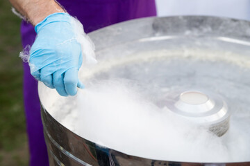 Cotton candy cooking, candyfloss machine. Male hand close up on the street