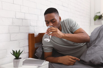 Black Man Taking Glass Of Water In Bed In Morning