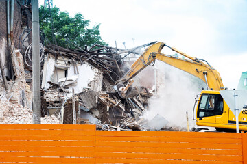 Building of the demolition. Yellow excavator working