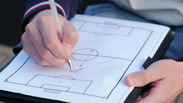 Football coach explains to players the tactics of conducting a match on a piece of paper