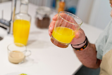 horizontal view of unrecognizable person drinking natural orange juice in the kitchen. Spanish breakfast preparation with fresh ingredients. Food and cooking concept.