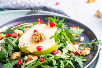 Fresh and healthy salad with arugula, gorgonzola cheese, pomegranate and pears.