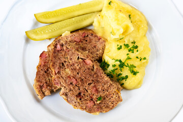 Fried chopped meat, mashed potato and pickled cucumber.