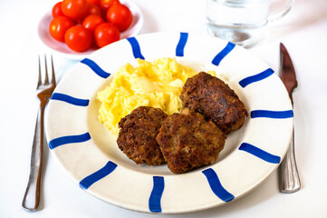 Fried meatball burger, mashed potato, cherry tomato and water.