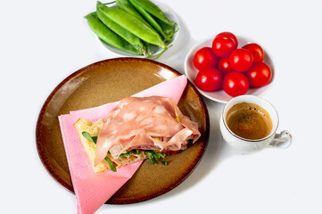 Bread with salami and rucola, cherry tomato and green pea pod, cup of espresso on white