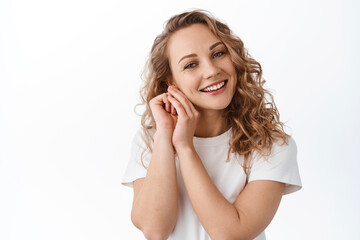 Portrait of blond lovely girl, contemplating beautiful and cute scene, gazing caring and heartfelt at camera, standing over white background