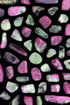 Ruby zoisite rare jewel stones texture on black surface background.