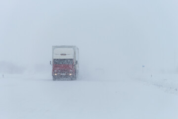 Snow storm on the road. Snowstorm on the road in winter. Cars on the highway in winter in a strong snowstorm. Poor visibility on the road. Bad weather conditions on the road.