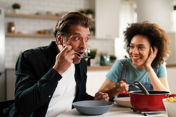 Boyfriend and girlfriend eating lunch together at home. Husband and wife enjoying in delicious food.