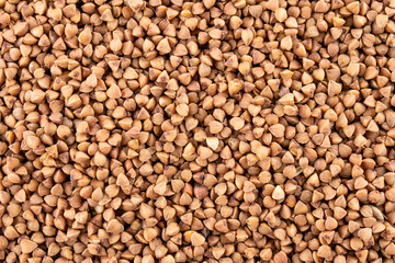 Buckwheat groats, texture background, top view, a pile of grain. Heap of brown core. Macro photo. Raw cereal, dieting nutrition concept. Kernel backdrop.
