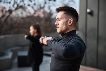 Handsome male joining fists while having tai chi training