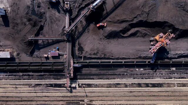 Coal mine. View from above. Coal transshipment. A large loader loads coal from a warehouse onto railroad cars.