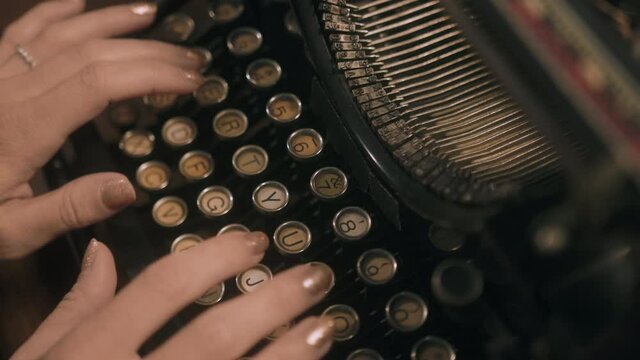Top down shot of woman's hands typing on vintage typewriter - slide across keys.