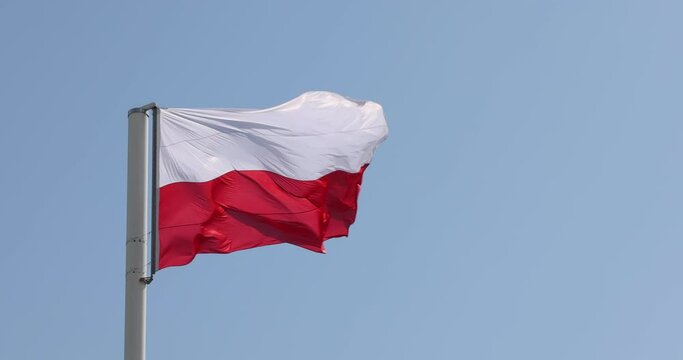 Polish flag on the mast. Beautiful Polish flag waving in a strong wind.