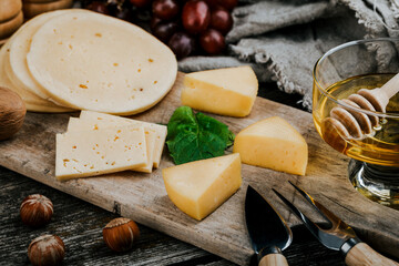 Cheese dish with organic cheeses, fruits, nuts on a wooden background. Delicious cheese snack