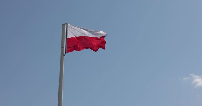 Polish flag on the mast. Beautiful Polish flag waving in a strong wind. Slow motion