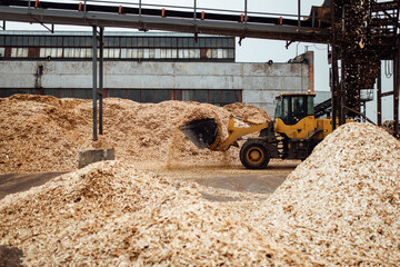 the excavator loads wood chips. the large bucket of the conveyor loads biofuels and wood mulch. industrial bulldozer is engaged in unloading slag