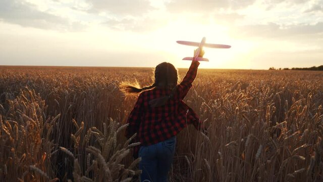 girl kid run with a toy airplane at sunset. kid dream childhood concept. girl child runs with an airplane toy silhouette in the park. carefree child dream outdoors silhouette. people in the park fun