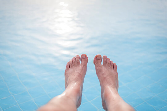 Overhead photo of feet on a background of water in swimming pool. Swimming pool, relax, health.