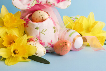 Colored Easter eggs in decorative basket and a bouquet of yellow narcissus