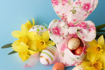 Colored Easter eggs in decorative basket and a bouquet of yellow narcissus