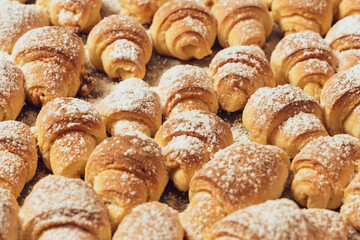 Homemade cakes, on a baking sheet fresh baked in the oven bagels made of cottage cheese dough sprinkled with powdered sugar