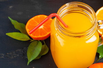Glass of orange juice and cut oranges on table