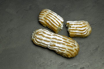 fresh cooked cakes with white cream and powdered sugar on a gray background