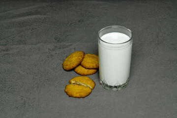 clear glass with milk and oat cookies on a gray background