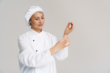 Asian mature woman in white chef uniform smiling and posing at camera