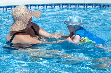 Family relaxing and having fun while playing together in swimming pool on summer break.