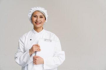 Asian mature woman in white chef uniform smiling and holding notepad