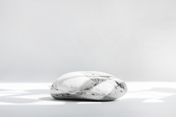 Background for cosmetics in natural white-gray color. Stone podium on a white background with hard shadows.