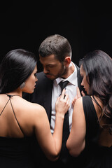elegant, brunette women near young man in suit isolated on black.