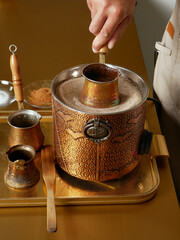 Traditional Turkish coffee brewed in heated sand. Preparation process by a barista.
