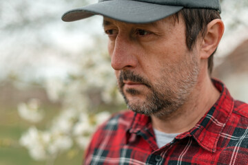Portrait of farmer inspecting in blooming cherry fruit tree orchard