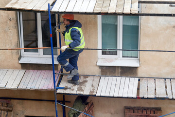 Fototapeta premium A builder installs wooden scaffolding to renovate an old house