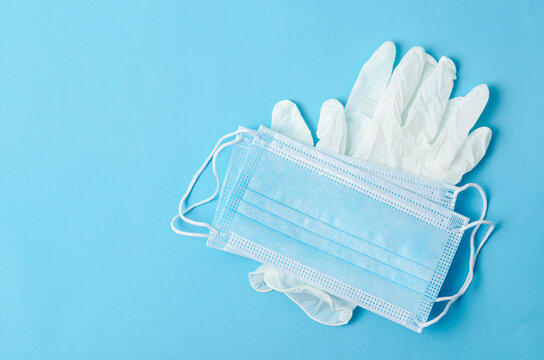 Medical face mask and glove on blue background.