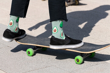 legs of teenager in green socks on a skateboard